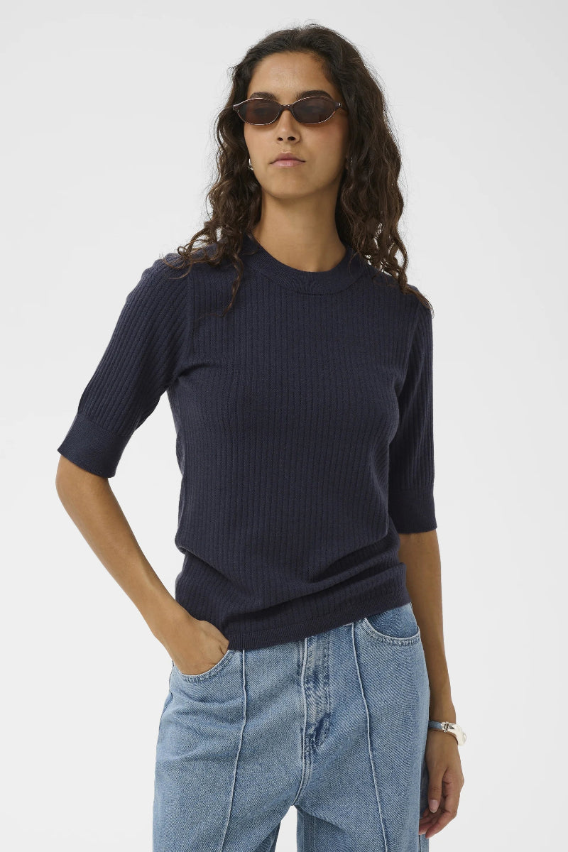 Person wearing a navy sweater and light blue jeans on a white background