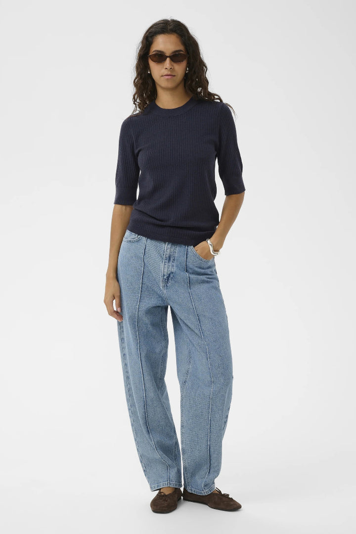 Person wearing a navy sweater and light blue jeans on a white background