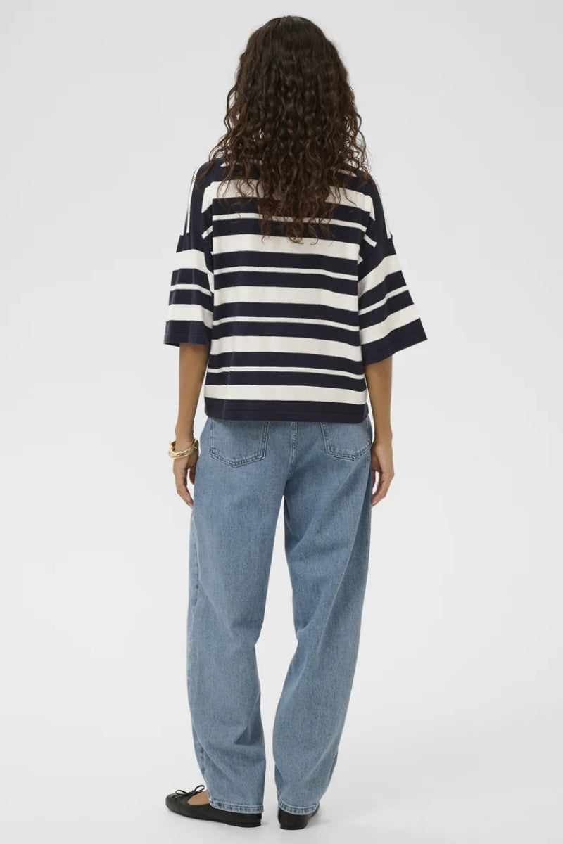 Person wearing a black and white striped shirt and blue jeans on a white background