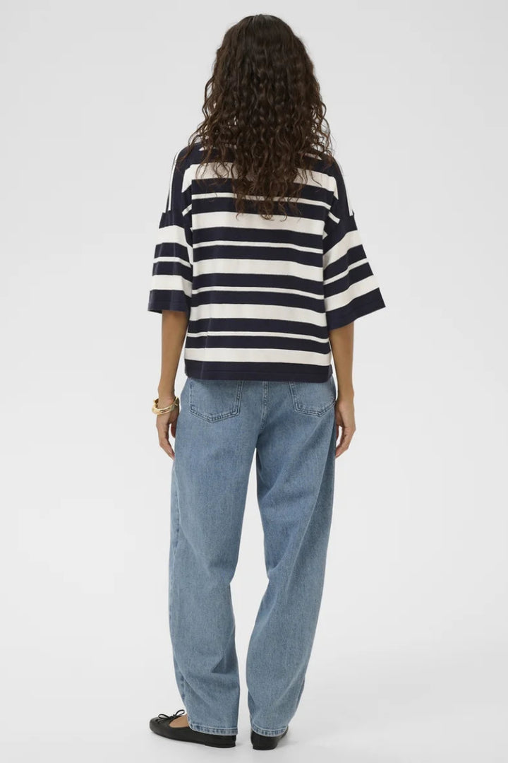 Person wearing a black and white striped shirt and blue jeans on a white background