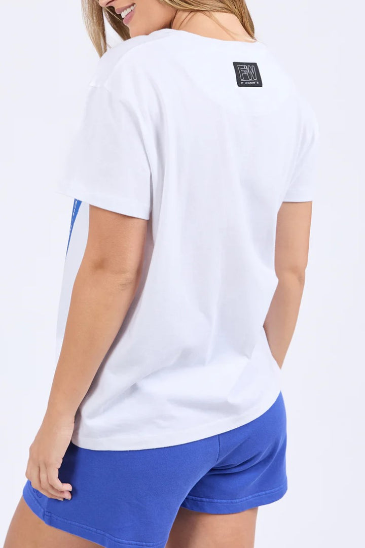 Person wearing a white t-shirt with a logo on the back and blue shorts.