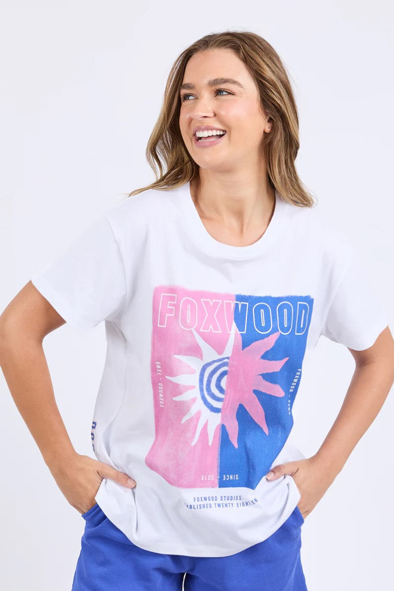 Woman wearing a white t-shirt with colorful graphic design on a plain background