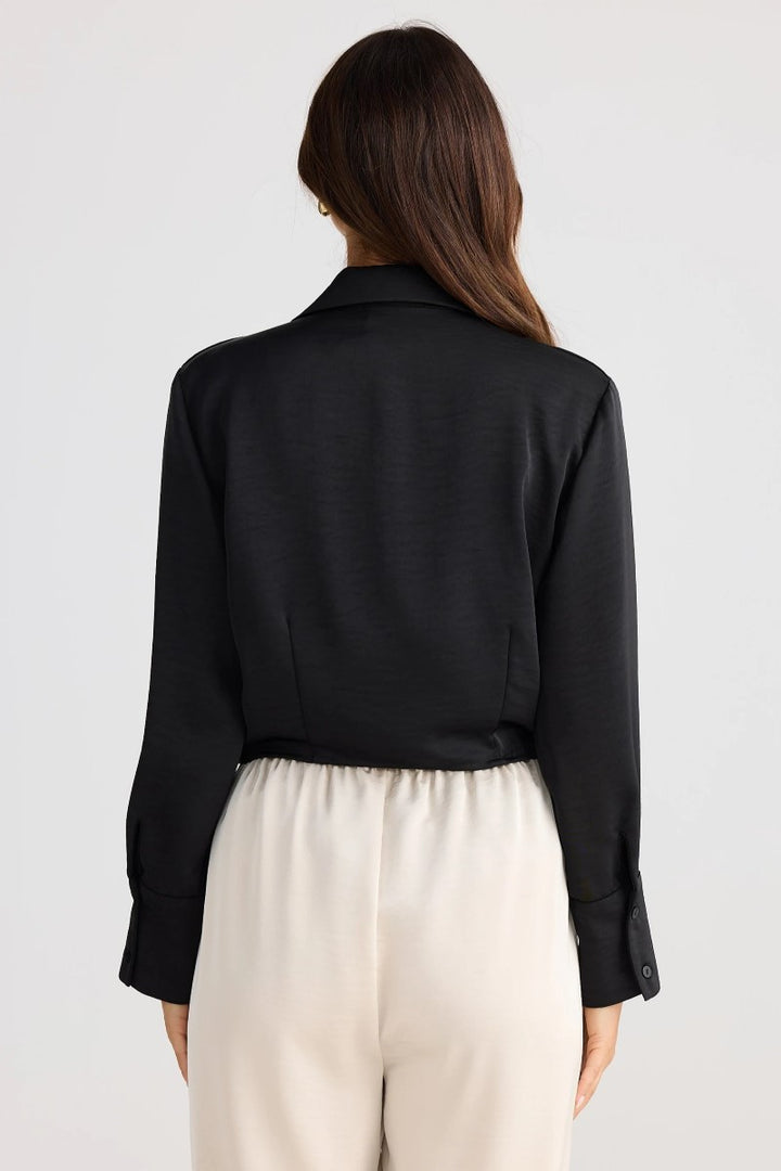 Person wearing a black shirt and beige pants on a white background
