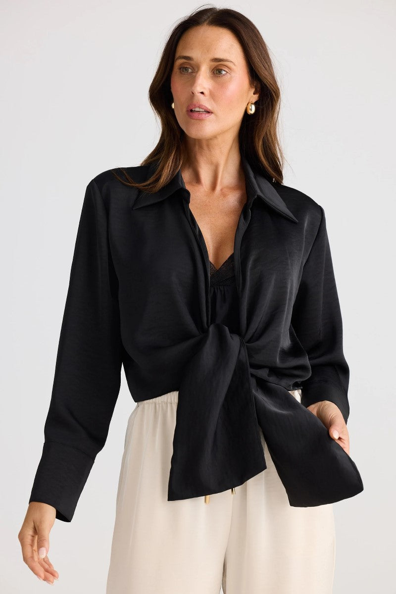 Woman wearing a black blouse with a knot detail on a white background