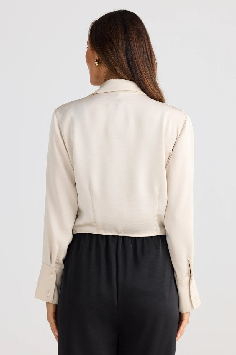 Person wearing a beige blouse and black pants on a light gray background