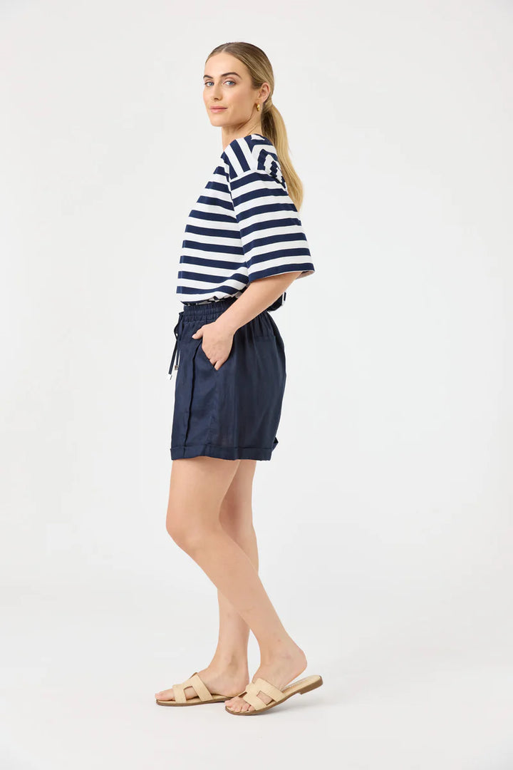 Woman wearing a striped shirt and navy shorts on a white background