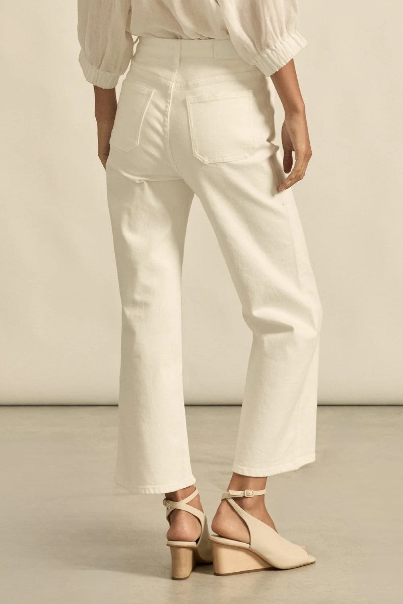 Person wearing white pants and beige sandals on a neutral background