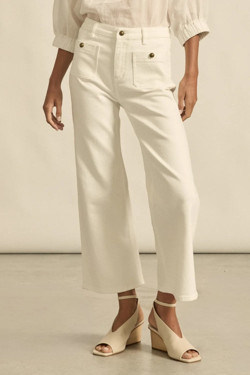 Person wearing white pants and a light-colored top on a neutral background