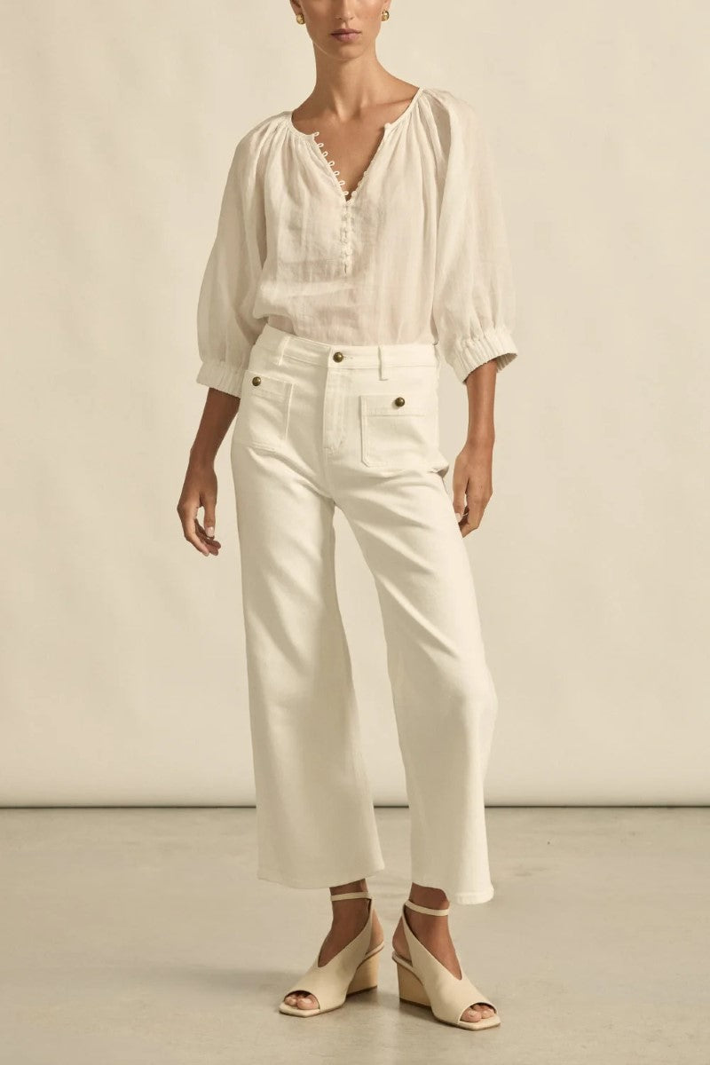 Person wearing a white blouse and pants against a neutral background