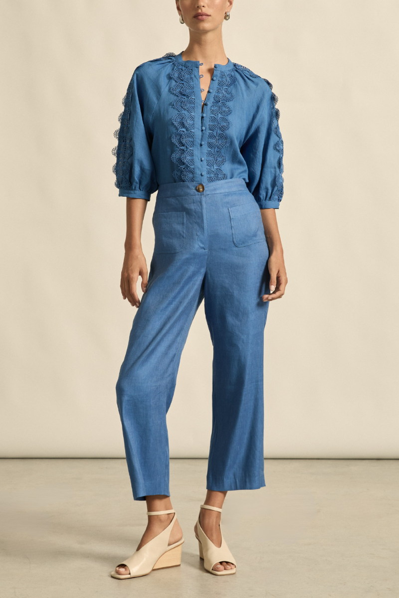 This front view of the Syllabus Pant in Shoreline showcases its tailored cropped silhouette, curved front patch pockets, and classic waistband with tortoise shell button.
