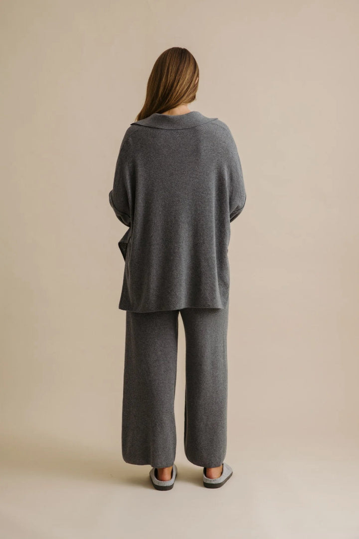 Person wearing a gray outfit standing against a beige background