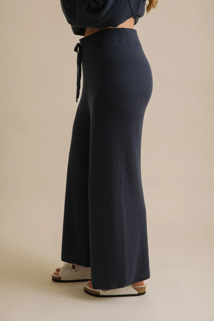 Navy blue wide-leg pants worn by a person on a beige background