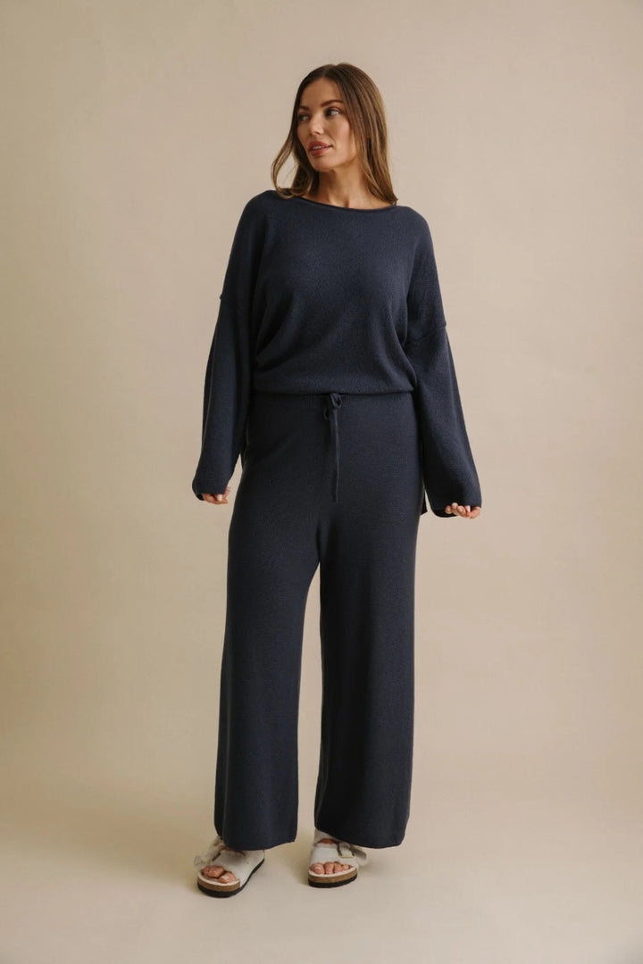 Woman wearing a navy blue outfit on a beige background