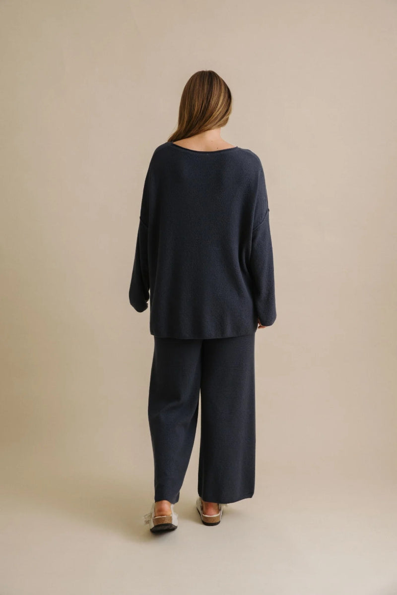 Person wearing a navy blue outfit on a beige background