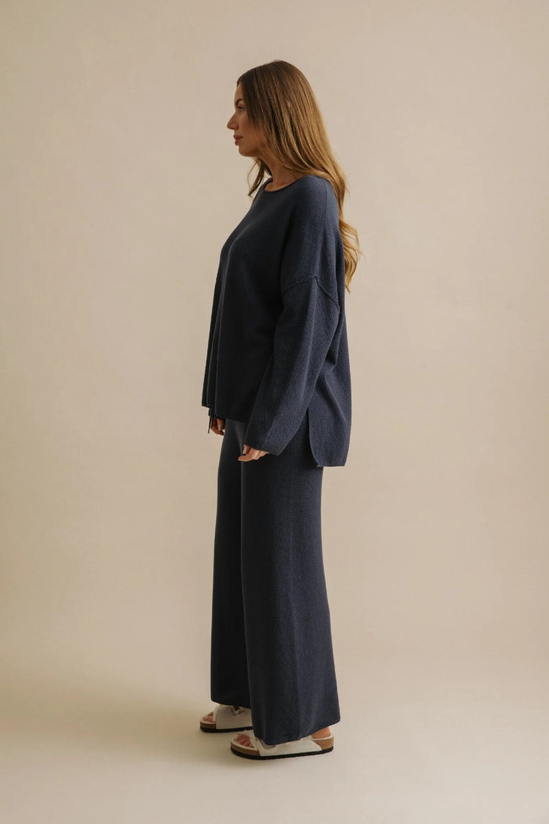 Woman wearing a navy blue outfit against a beige background