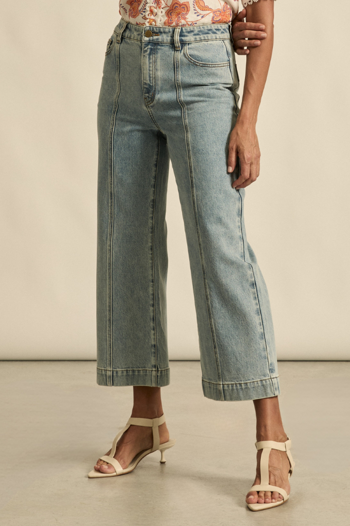Close-up front view of the Tenure Jean in washed denim, showcasing the classic button and zip closure, front pockets, and detailed denim texture.