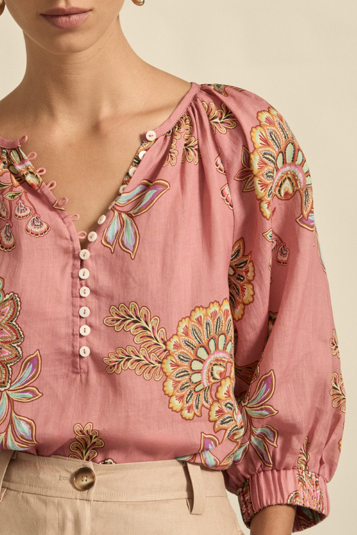 This close-up image of the Tranquil Top in Kgari Bloom highlights the intricate gathers at the neckline, delicate shell buttons, and the lightweight ramie fabric.
