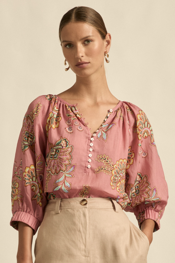 This front close-up view of the Tranquil Top in Kgari Bloom highlights the gathered neckline, delicate shell buttons, and the soft texture of the 100% ramie fabric.
