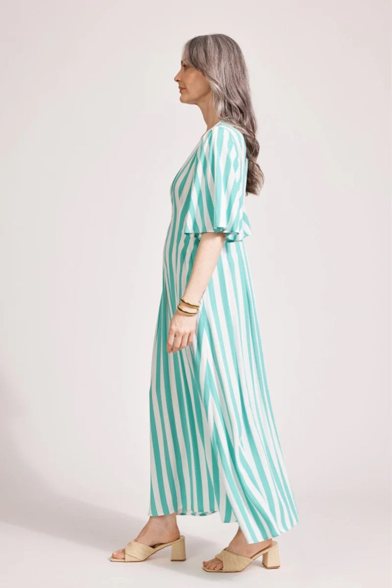 Woman wearing a green and white striped dress against a plain background