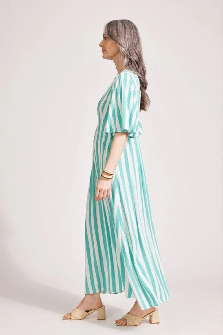 Woman wearing a green and white striped dress against a plain background