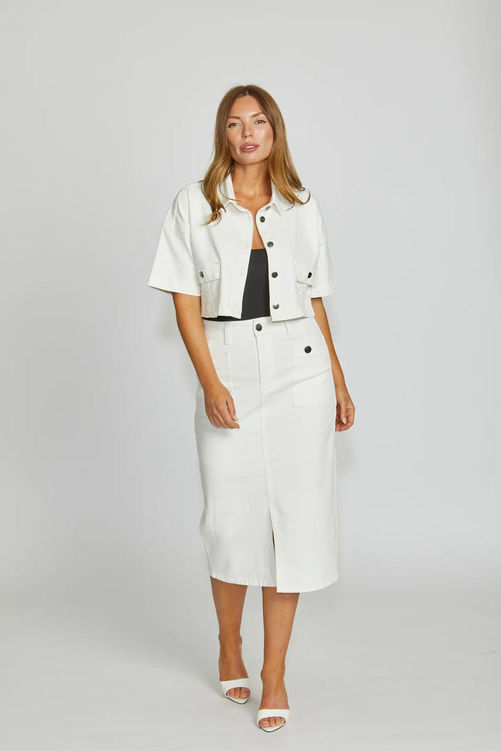 Woman wearing a white jacket and skirt set on a plain background