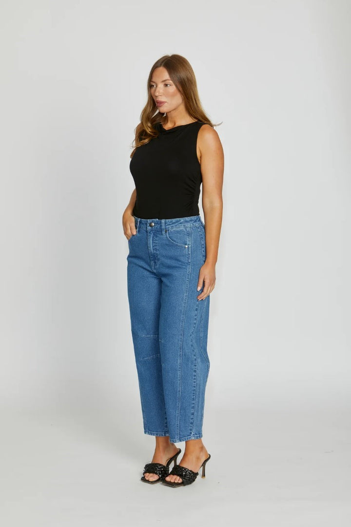 Woman wearing a black top and blue jeans on a white background