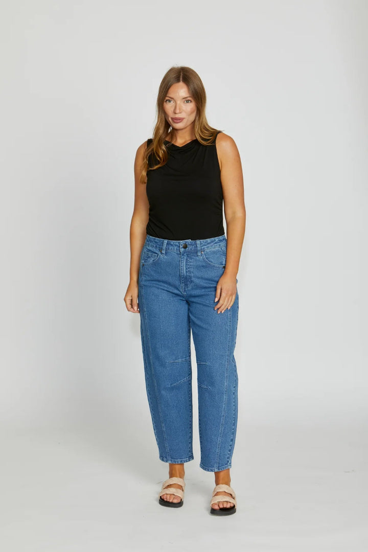 Woman wearing a black sleeveless top and blue jeans on a white background