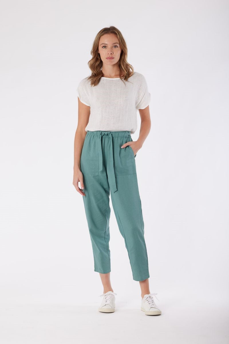 Woman wearing a white top and green pants on a white background
