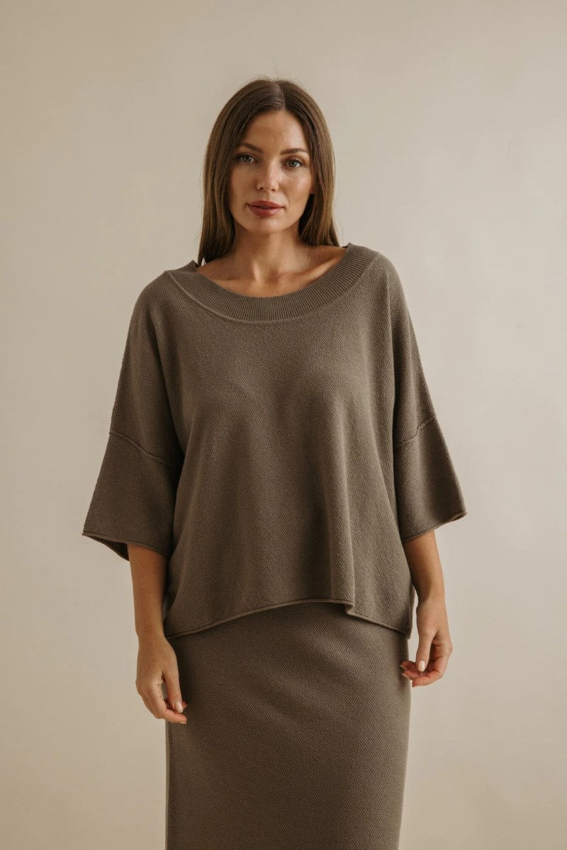 Woman wearing a brown outfit against a beige background