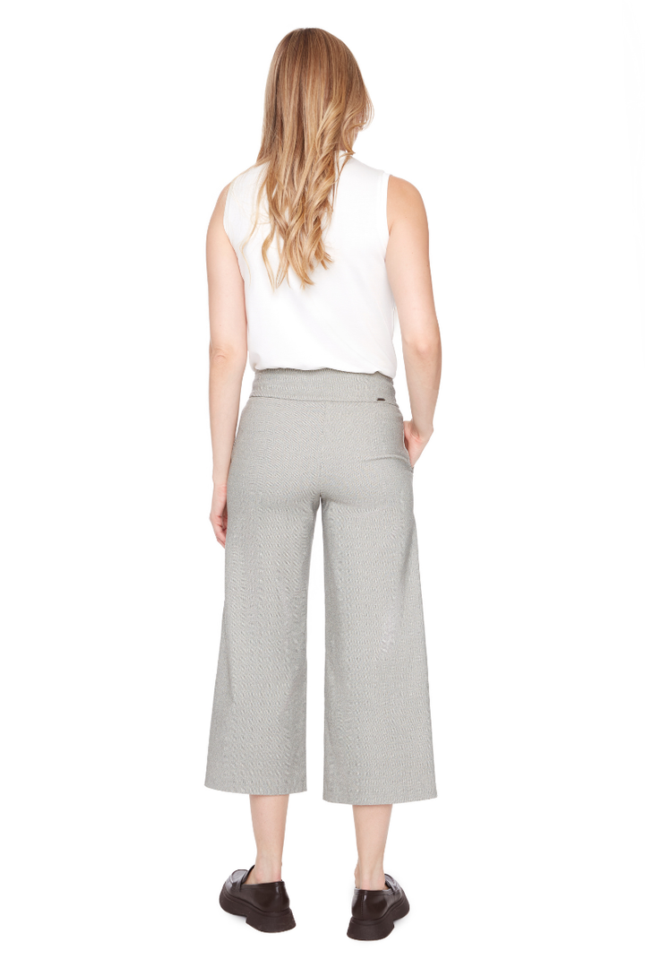 Woman wearing a white sleeveless top and gray wide-leg pants on a white background