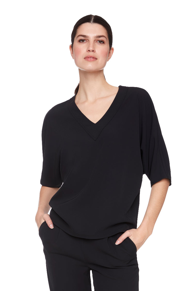 Woman wearing a black V-neck top and black pants on a white background