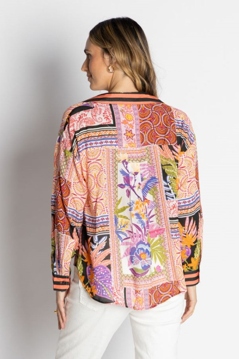 Woman wearing a colorful patterned blouse against a white background