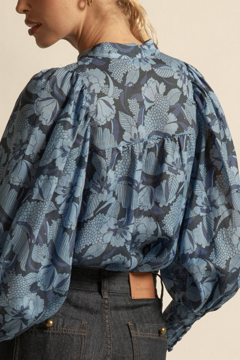 Woman wearing a floral blue blouse  front buttons on a beige background