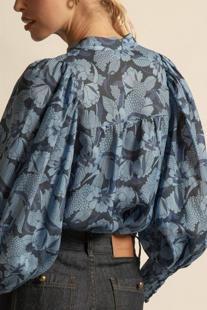 Woman wearing a floral blue blouse  front buttons on a beige background