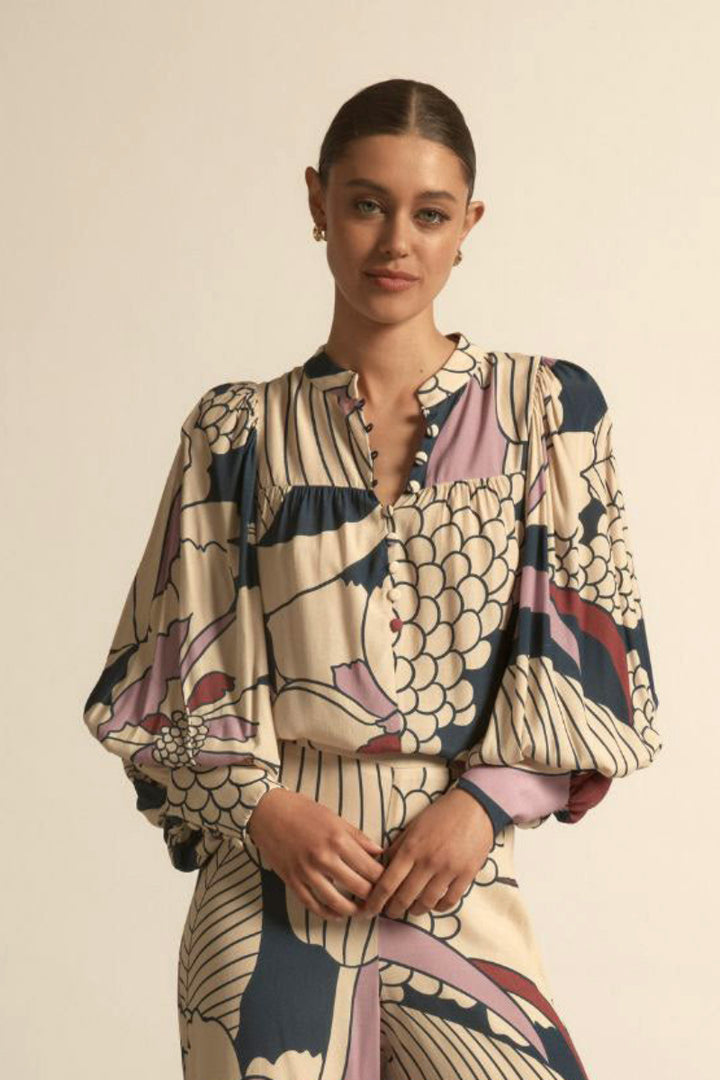 Woman wearing petals print with purple, red and blue accents on a beige background