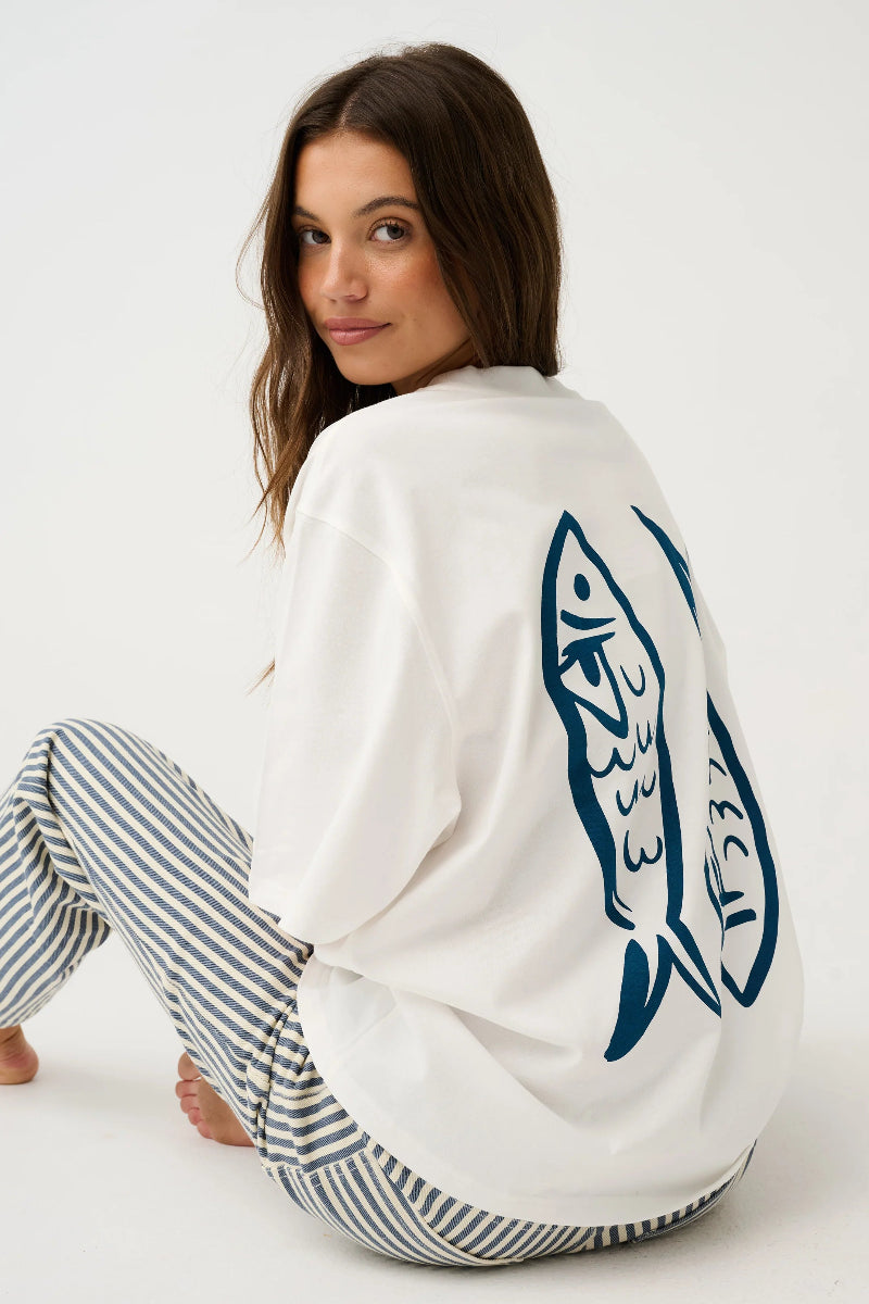 Side seated view of white oversized fish graphic T-shirt.