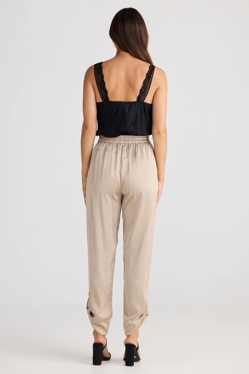 Woman wearing a black top and beige pants on a white background