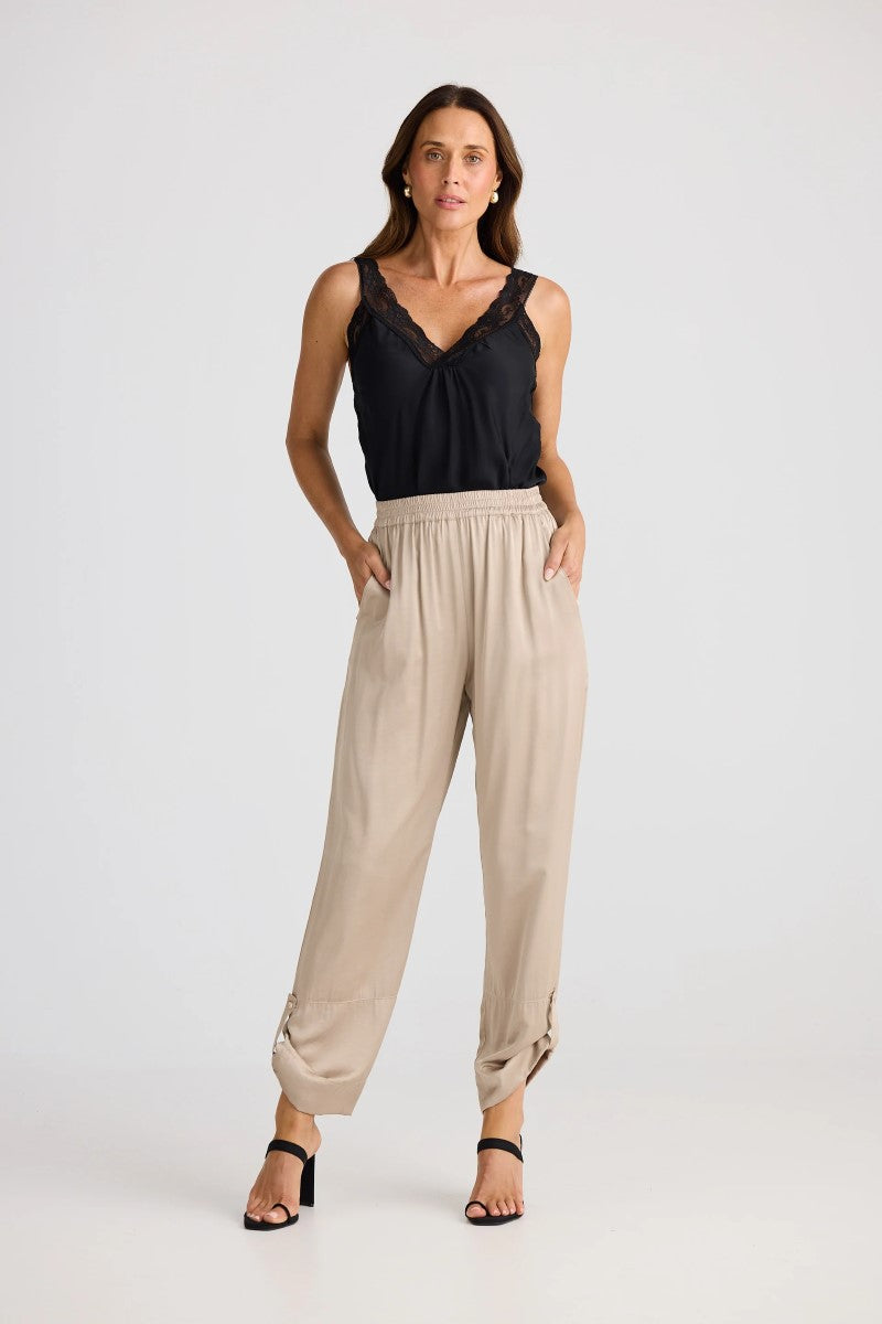 Woman wearing a black top and beige pants on a white background