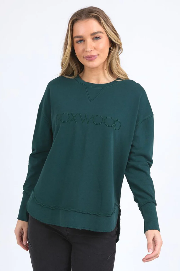 Woman wearing a green sweatshirt with 'Foxwood' branding on a white background