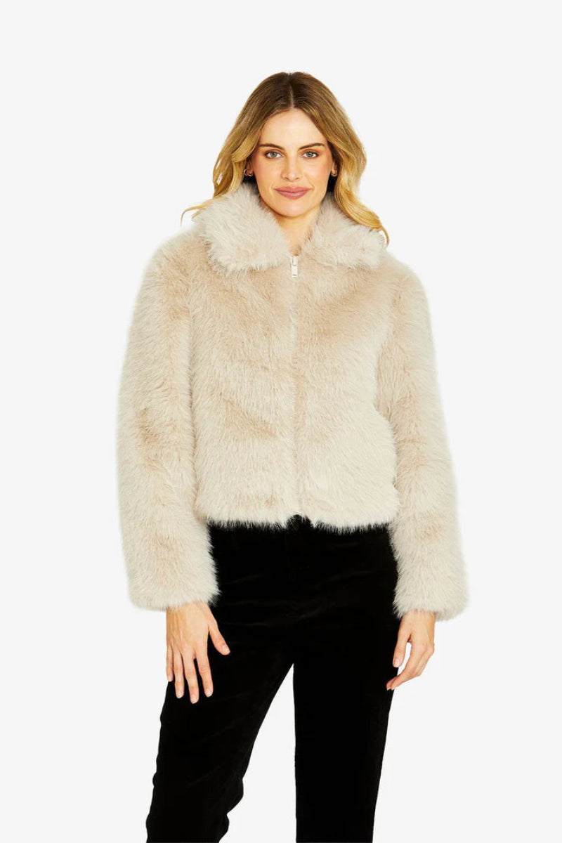 Woman wearing a beige fur jacket on a white background