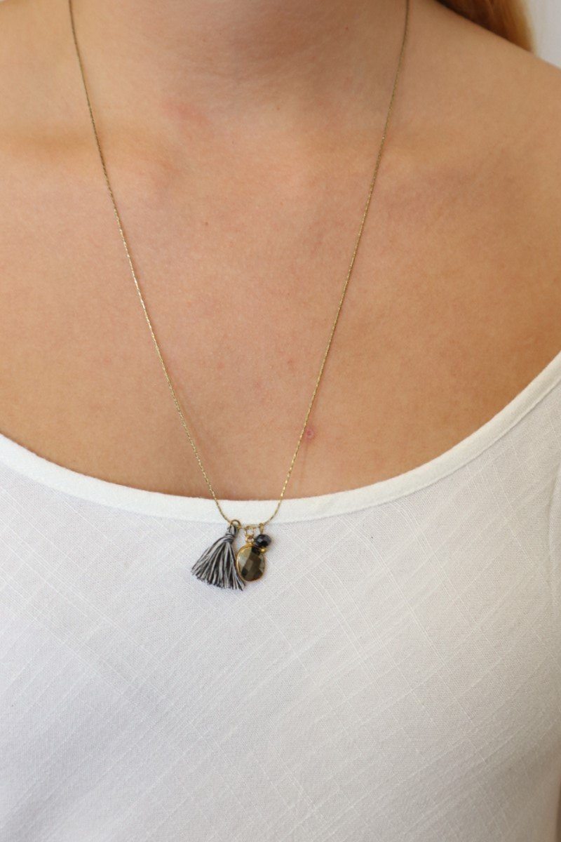 milla necklace on a gold chain with off white tones, stones and tassels